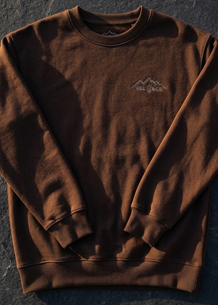Brown sweatshirt with a logo on a dark textured surface