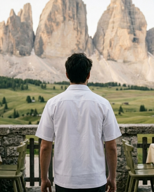 Man standing in front of a scenic view with mountains and tables in the foreground