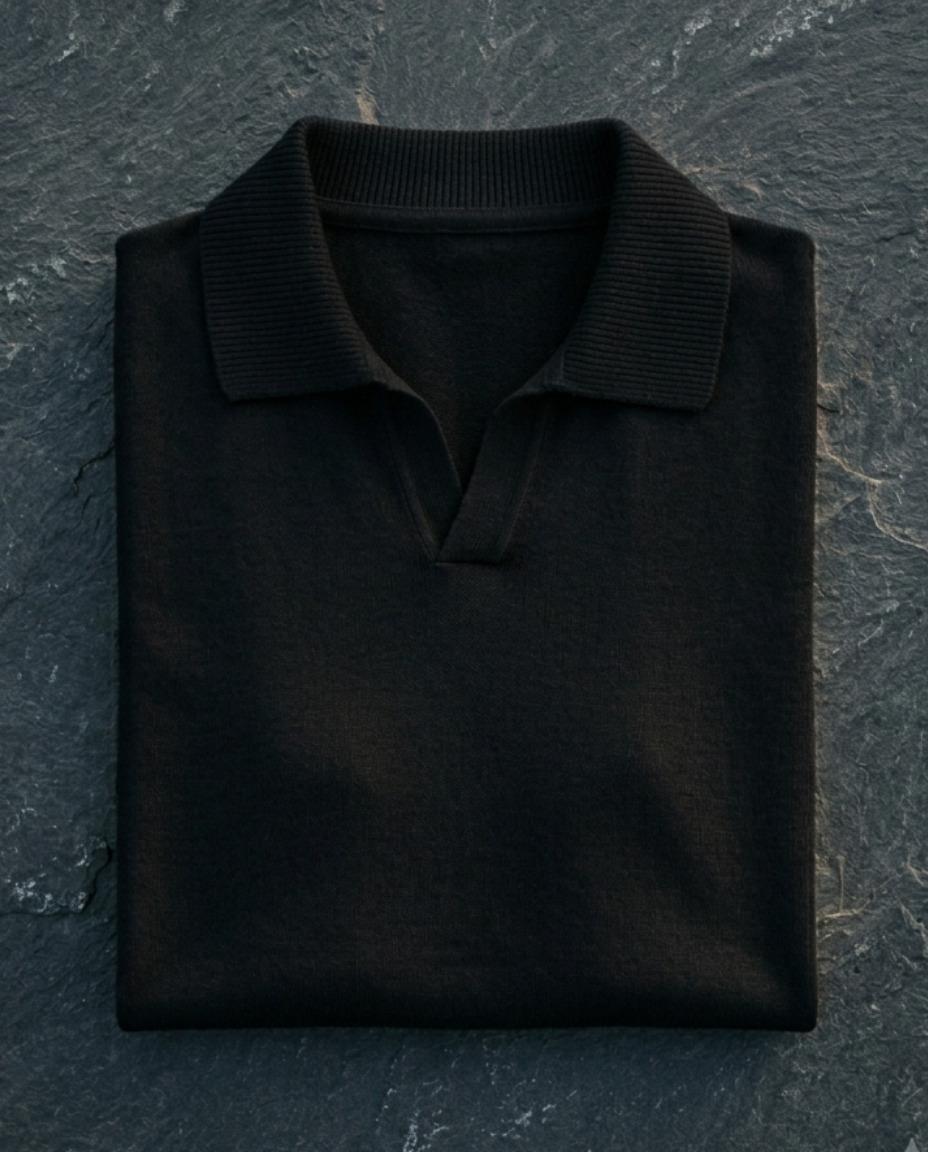 Folded black polo shirt on a dark stone surface