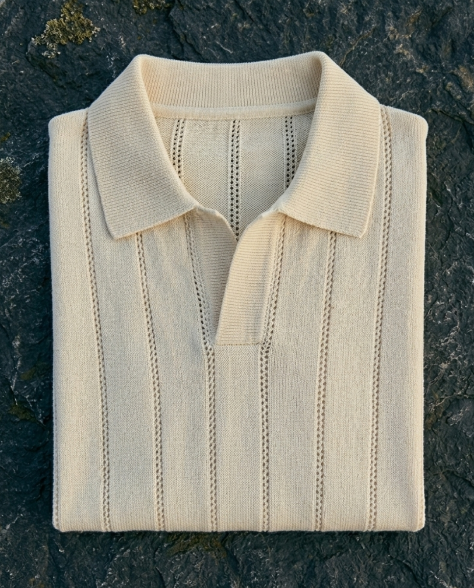 Folded cream-colored polo shirt on a dark stone surface